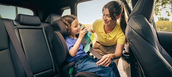 Mamma sätter på bilbälte på dottern